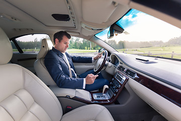 Image showing Businessman using cell phone and texting while driving not paying attention to the road.