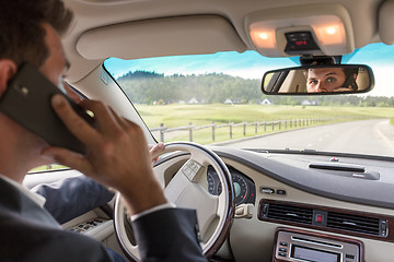 Image showing Man talking on cell phone while driving not paying attention to the road.
