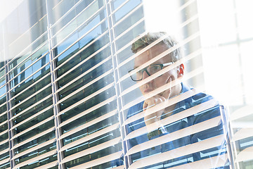 Image showing Casual businessman working in office, sitting at desk, typing on keyboard, looking at computer screen.