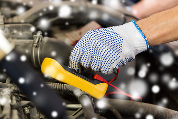 Image showing auto mechanic with multimeter testing battery