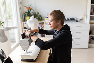 Image showing fashion designer with sewing machine at studio