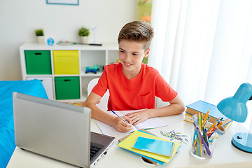 Image showing student boy with laptop writing to notebook