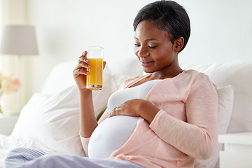 Image showing pregnant woman drinking orange juice in bed
