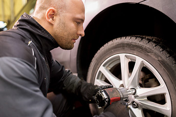 Image showing auto mechanic with screwdriver changing car tire