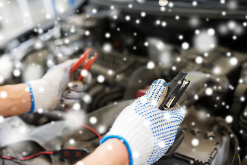 Image showing auto mechanic hands with cleats charging battery