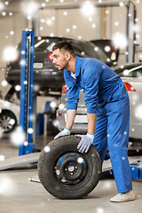 Image showing auto mechanic changing car tire at workshop