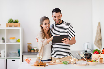 Image showing happy couple with tablet pc cooking food at home