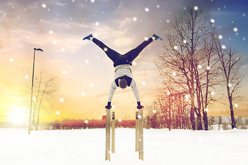 Image showing young man exercising on parallel bars in winter