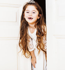 Image showing little cute girl at home, opening door well-dressed in white dre