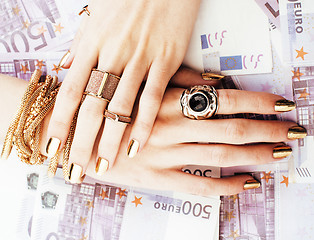 Image showing hands of rich woman with golden manicure and many jewelry rings on cash euros