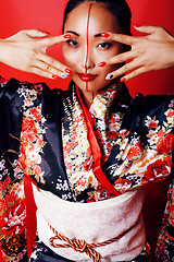 Image showing young pretty geisha on red background posing in kimono, oriental people concept close up