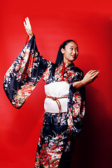 Image showing young pretty geisha on red background posing in kimono, oriental people concept close up