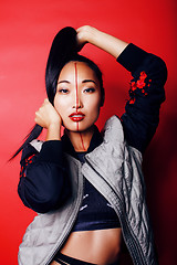Image showing young pretty asian girl posing cheerful on red background, fashion style makeup and hair, lifestyle modern orient people concept