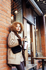 Image showing young pretty african american women drinking coffee outside in c