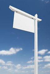 Image showing Blank Real Estate Sign Over A Blue Sky with Clouds.