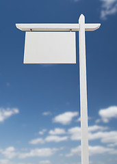 Image showing Blank Real Estate Sign Over A Blue Sky with Clouds.