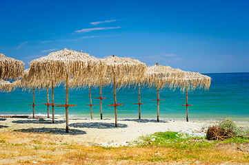 Image showing reed umbrellas at empty beach