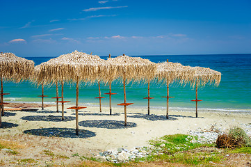 Image showing reed umbrellas at empty beach