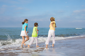 Image showing Three happy children running on the beach at the day time.