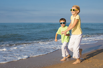 Image showing Two happy children running on the beach at the day time.