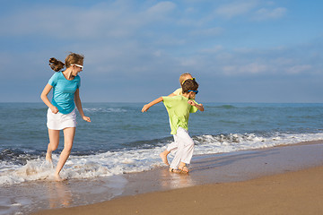 Image showing Three happy children running on the beach at the day time.