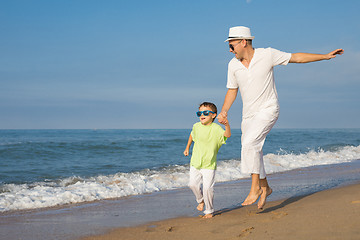 Image showing Father and son running on the beach at the day time.