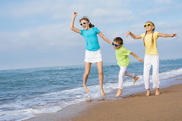 Image showing Three happy children running on the beach at the day time.