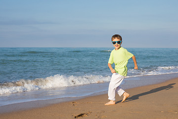 Image showing  happy little boy running on the beach at the day time. 