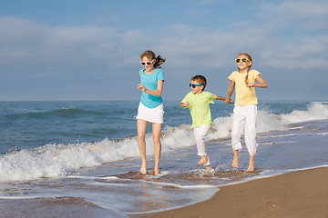 Image showing Three happy children running on the beach at the day time.