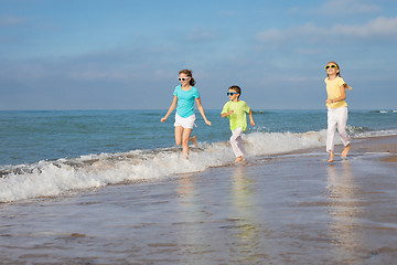 Image showing Three happy children running on the beach at the day time.