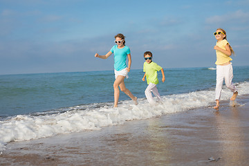 Image showing Three happy children running on the beach at the day time.