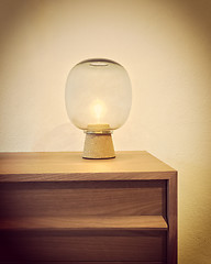 Image showing Retro style glass lamp on a wooden dresser