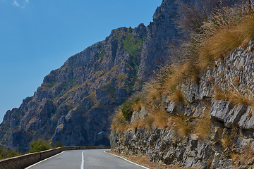 Image showing Asphalt road. Colorful landscape with beautiful mountain road with a perfect asphalt. High rocks, blue sky at sunrise in summer. Vintage toning. Travel background. Highway at mountains