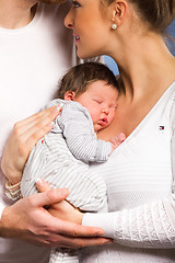 Image showing Portrait of young happy couple embracing to their newborn.