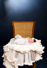 Image showing Newborn baby girl with sleeping on a wooden chair