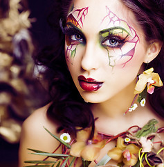 Image showing beauty woman with face art and jewelry from flowers orchids clos