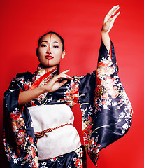 Image showing young pretty geisha on red background posing in kimono, oriental people concept 