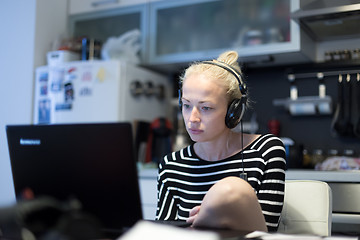 Image showing Adult woman in her casual home clothing working and studying remotely from her small flat late at night.