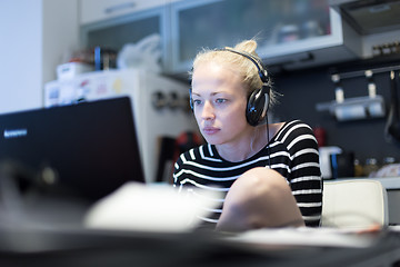 Image showing Adult woman in her casual home clothing working and studying remotely from her small flat late at night.