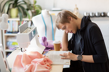 Image showing fashion designer reading book at studio