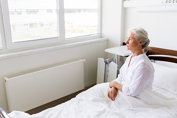 Image showing sad senior woman sitting on bed at hospital ward