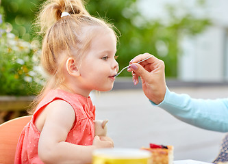 Image showing mother hand with spoon feeding daughter at cafe