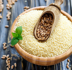 Image showing Scoop with wheat in a wooden bowl with couscous.