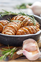 Image showing Potatoes in their skins baked with rosemary.