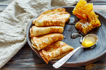 Image showing Crepes with honey on a wooden plate.