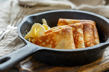 Image showing Delicious crepes with butter in a cast iron pan.