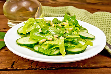 Image showing Salad from spinach and cucumber with napkin on board