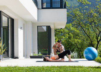 Image showing woman with personal trainer doing morning yoga exercises