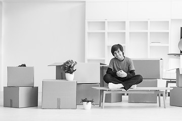 Image showing boy sitting on the table with cardboard boxes around him