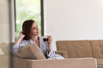 Image showing young woman in a bathrobe enjoying morning coffee